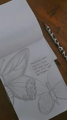 a drawing of two butterflies on top of a piece of paper next to a pen