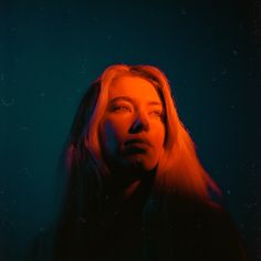 a woman with long hair standing in front of a blue background