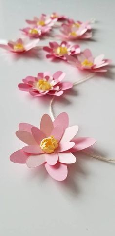 pink paper flowers with gold centers on a string