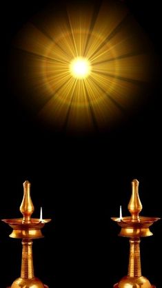 two golden candlesticks sitting on top of each other in front of a black background