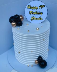 a white cake with black and gold decorations on it's top, sitting in a blue box