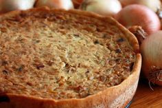 a pie sitting on top of a wooden table next to onions