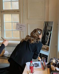 a woman sitting at a desk with an easel in front of her