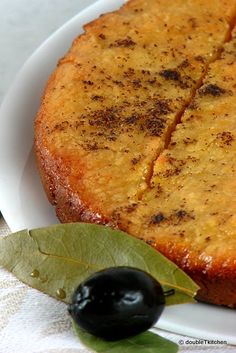 a close up of a cake on a plate with a leaf and some olives