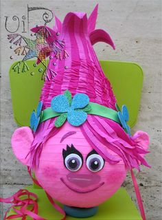 a pink troll sitting on top of a green chair