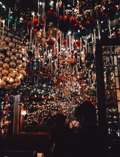 people are standing in front of a christmas tree with ornaments hanging from it's ceiling