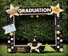 a graduation photo frame decorated with gold stars and confetti on the grass in front of a hedge