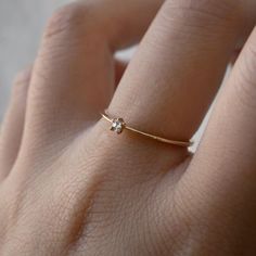 a woman's hand wearing a gold ring with a small diamond on the side