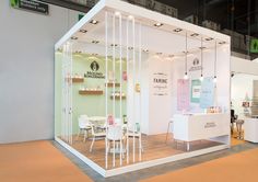 a white booth with tables and chairs on display in an indoor space that is well lit