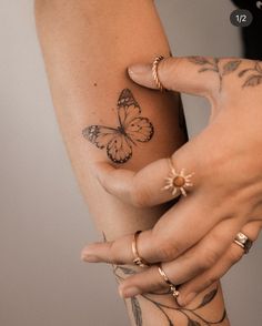 a woman with tattoos on her arm holding onto another person's wrist and butterfly tattoo