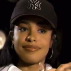 a close up of a person wearing a baseball cap and holding a microphone in front of her face