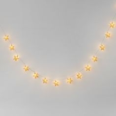 a string of yellow stars is hanging from the side of a white wall with lights on it