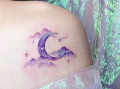 a woman's shoulder with a crescent moon tattoo on her left shoulder and stars in the sky