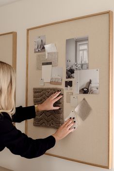 a woman is placing pictures on a bulletin board