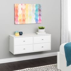 a bedroom with a white dresser and colorful painting on the wall above it's bed