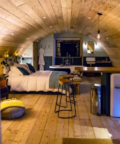 an attic bedroom with wood floors and wooden walls, has a bar stool in the corner