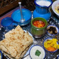 a table topped with plates and bowls filled with food next to containers of sauces