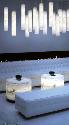 a living room filled with white couches and lights hanging from the ceiling above them