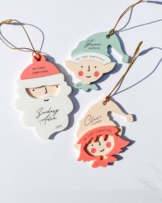 three christmas ornaments hanging from strings on a white surface