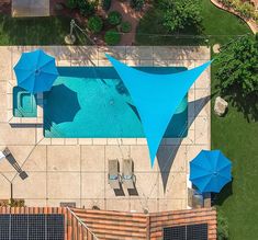 an aerial view of a swimming pool with blue umbrellas