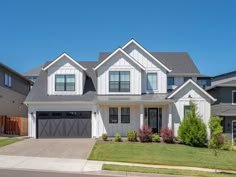 a large white house with two garages on the front and one car in the driveway