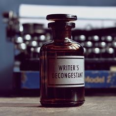 an old fashioned typewriter sitting on top of a wooden table next to a bottle