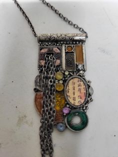 This is a previously owned Steam Punk Necklace. It is made up of a collage of pictures and rhinestones. It is mostly green and gold in color. It is in good condition. The chain measures 18" and the longest chain hangs 3". It is silver tone with enamel. It has rhinestones of different colors throughout. The pendant measures 2" wide by 1" tall.⁸ A Collage Of Pictures, Collage Of Pictures, Punk Collage, Punk Necklace, A Collage, Steam Punk, Long Chain, Green And Gold, Pendant Necklaces