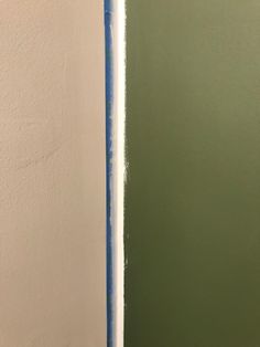 the wall is painted green and white with blue tape on it's edges,