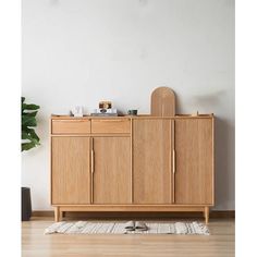 a large wooden cabinet sitting on top of a hard wood floor next to a potted plant