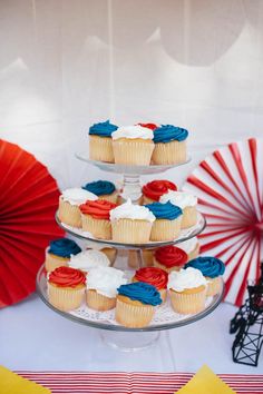 three tiered cake stand with cupcakes on it and red white and blue decorations