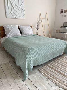 a large bed sitting on top of a wooden floor next to a white wall with a painting hanging above it