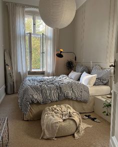 a bed room with a large bed and a big lamp hanging from the ceiling next to a window