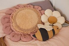 a stuffed bee sitting on top of a bed next to a pillow with a flower