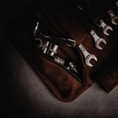 two wrenches in a leather pouch on the floor next to other tools and gadgets