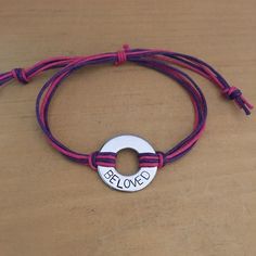 a purple cord bracelet with a silver plate that says blonqd on it