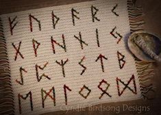 an old fashioned cross stitch alphabet is displayed on a tablecloth with a spoon next to it