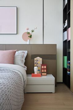 a bedroom with a bed, bookshelf and vase on the end table in front of it