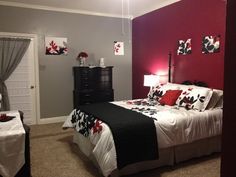 a bedroom decorated in red and black with flowers on the bed, nightstands and lamps