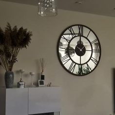 a living room filled with furniture and a large clock mounted to the wall above it