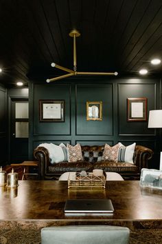 a living room with couches, tables and pictures on the wall above them is dark wood paneling