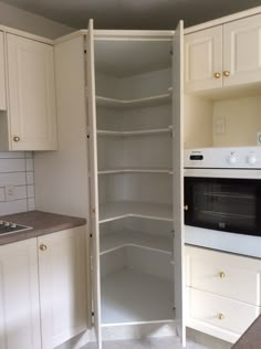 an empty pantry in the middle of a kitchen with white cupboards and drawers on both sides