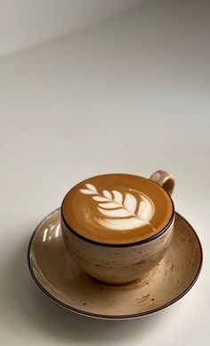 a cappuccino on a saucer with a leaf design in the middle