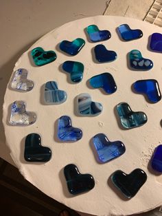 a white plate topped with lots of blue and green heart shaped glass pieces on top of it