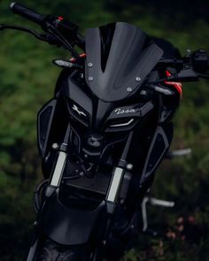 a black motorcycle parked on top of a lush green field