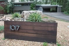 a large wooden planter sitting in front of a house with the number seventy on it