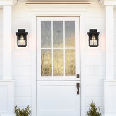 a white house with two lights on the front door and sidelights on the wall