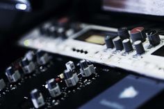 an electronic mixing console with multiple knobs and controls on it's side, in front of a computer screen