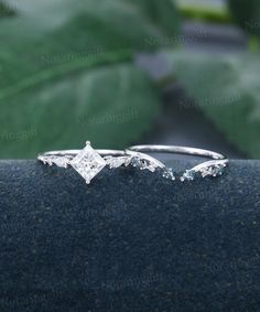 two white gold engagement rings with diamonds on the side and leaves in the back ground