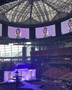 a large stadium filled with lots of people watching women on big screen tv's