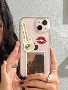 a woman holding up a phone case with stickers on it and an image of a guitar